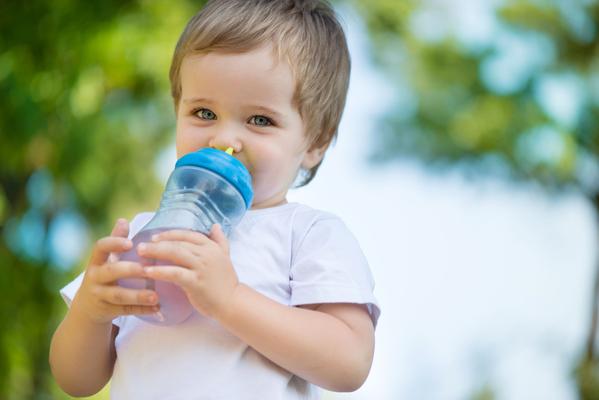 Toddler boy drinking milk from baby bottle stock photo - OFFSET